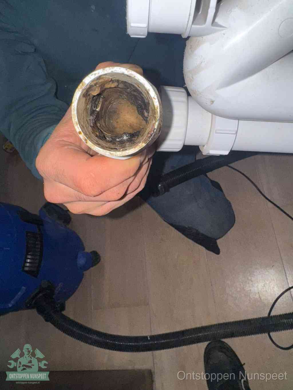 Een losgekoppeld PVC-afvoerbuisstuk dat van binnen volledig is dichtgeslibd met vet en vuil, de meest voorkomende oorzaak van verstoppingen in Nunspeet