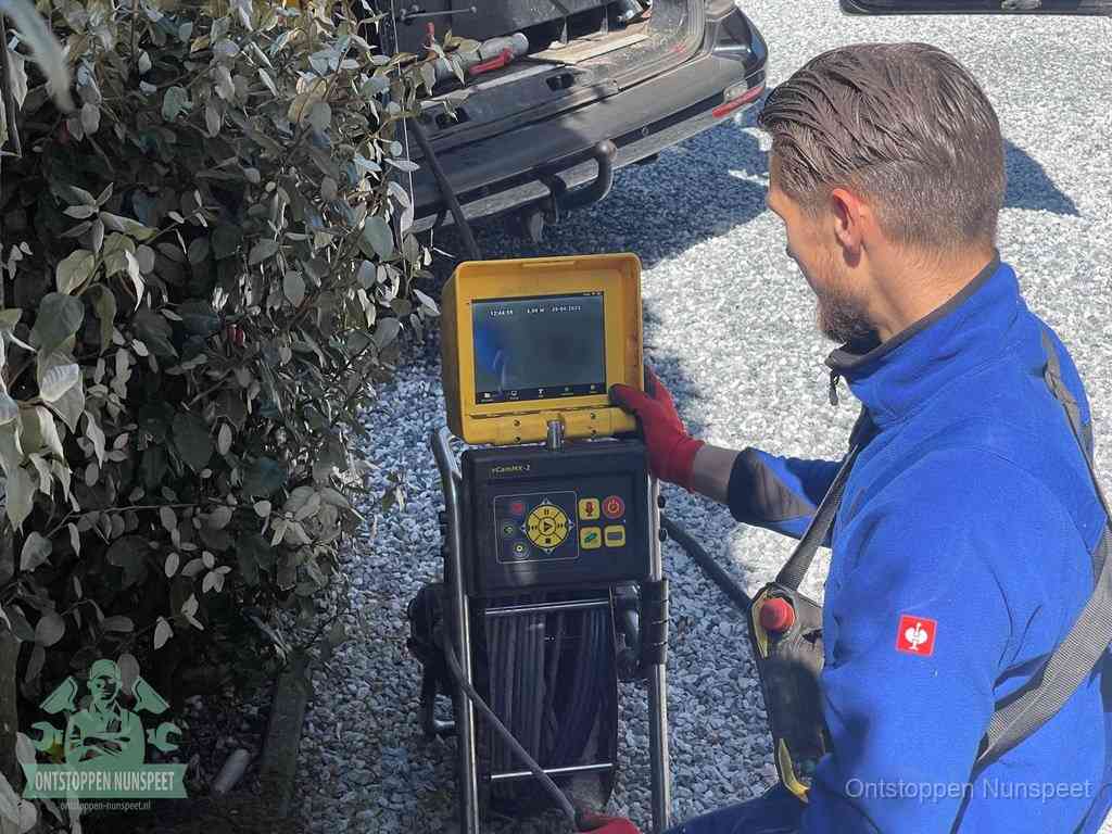 Een monteur bedient een rioolinspectiecamera met monitor en haspel om de verstopping in beeld te brengen in Nunspeet
