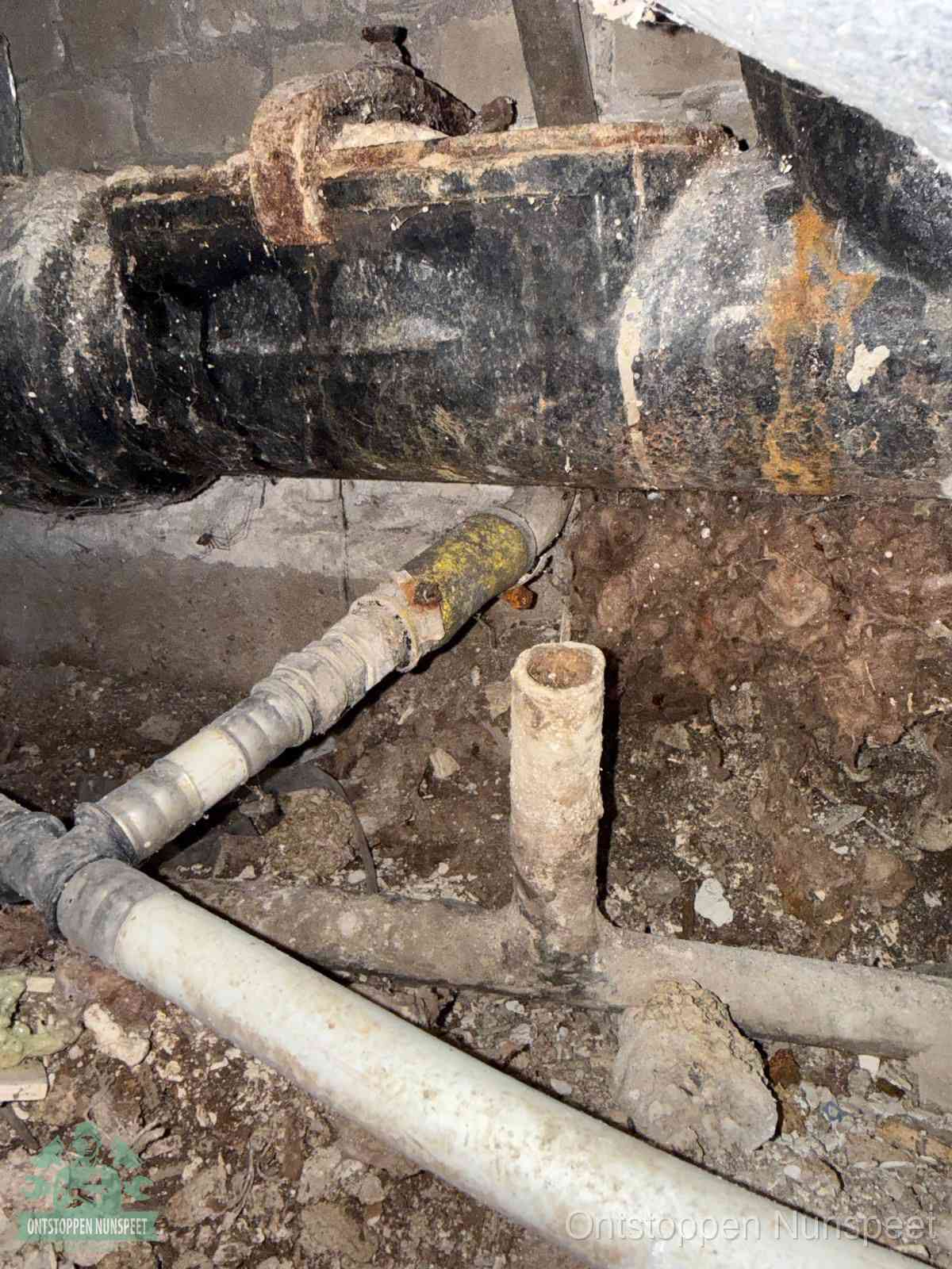 Een oude hoofdrioolbuis met roest- en kalkaanslag in een kruipruimte, oorzaak van terugkerende structurele rioolproblemen in Nunspeet